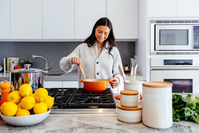 Woman is having fun cooking on the stovetop.