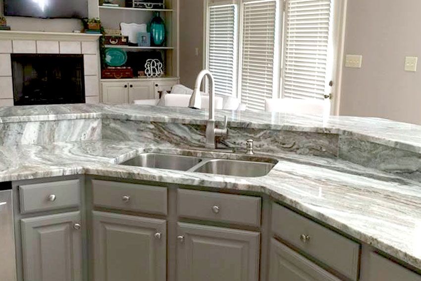 Kitchen sink with a marble curved countrtop and backsplash.