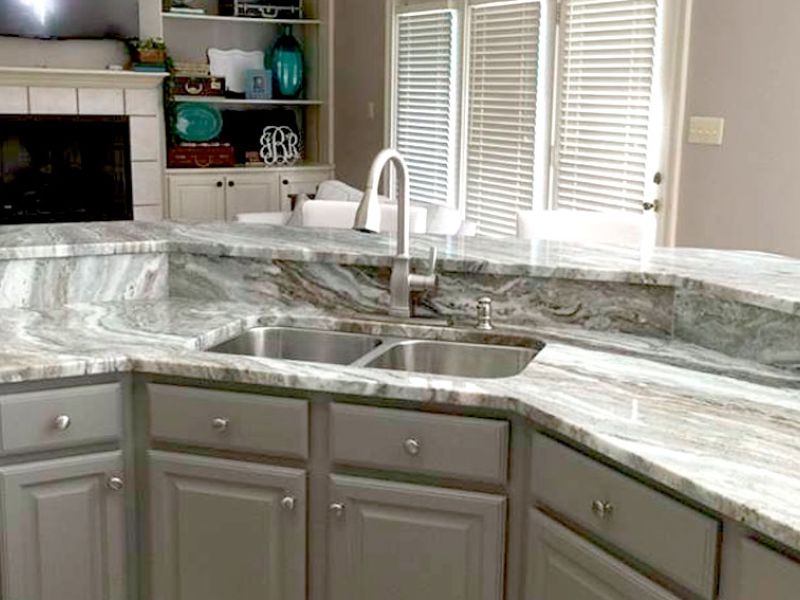 Kitchen sink with a marble curved countrtop and backsplash.